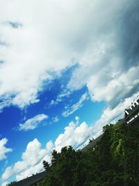 Low angle view of trees against cloudy sky