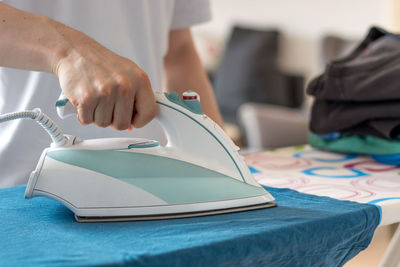 Midsection of man ironing garment on board