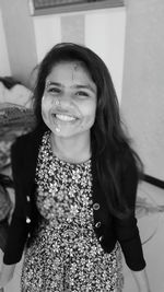 Portrait of smiling teenage girl standing at home