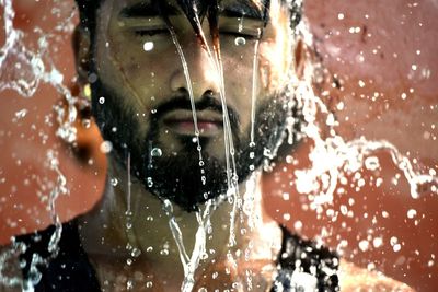 Close-up portrait of wet man splashing water