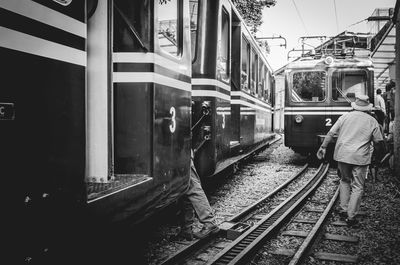 Rear view of people standing on railway tracks