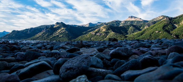 Scenic view of pebbles and mountains against sky