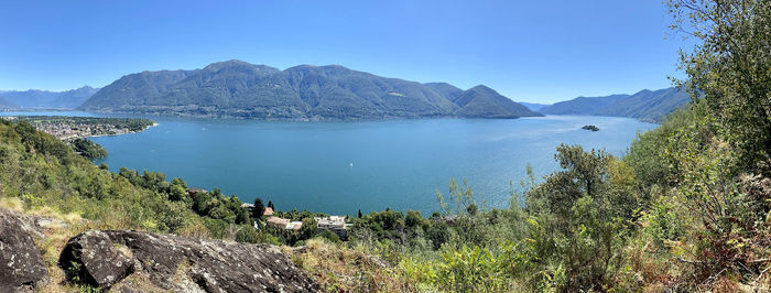 Scenic view of lake and mountains against clear blue sky