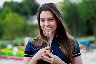 Close-up portrait of smiling woman holding lollipop 