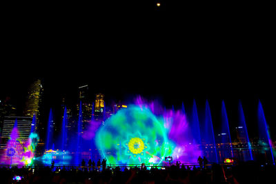 Panoramic view of crowd at music concert against sky at night