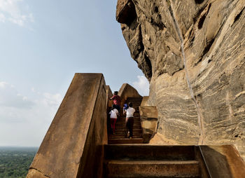 People on rock against sky