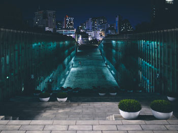 Illuminated footpath amidst buildings in city at night