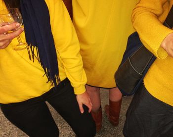 Midsection of people holding yellow dress