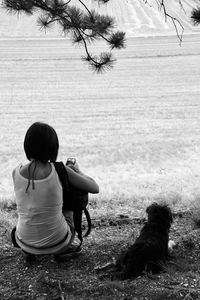 Rear view of woman with dog crouching on land