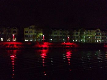 Illuminated city by river at night