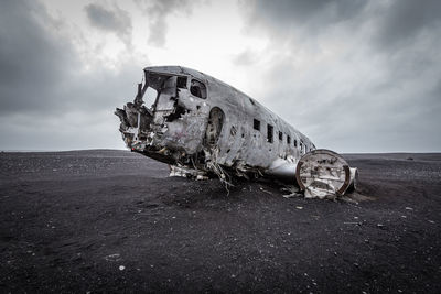 Abandoned airplane on land against sky