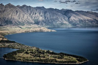 Scenic view of sea by mountains against sky