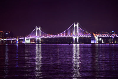 Illuminated diamond bridge over sea against sky at night