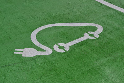 High angle view of electric car symbol on green road