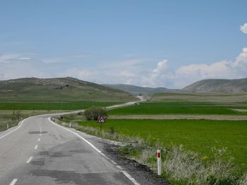 Road amidst green landscape against sky