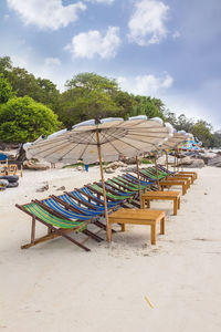 Empty chairs on beach against sky