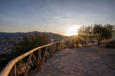 Rear view of man walking on footbridge against sky during sunset