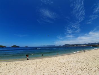 People on beach against blue sky