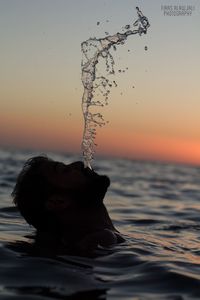 Close-up of splashing water against sky at sunset