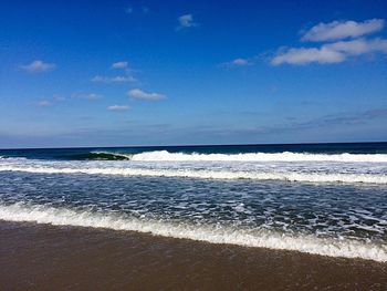 Scenic view of beach against blue sky