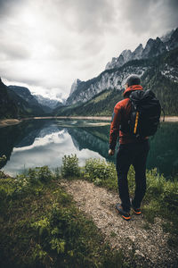 Rear view of man standing by lake against mountains