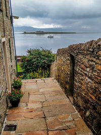 Stone wall by sea against sky