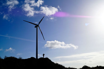 Low angle view of windmill on hill against sky