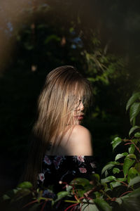 Portrait of young woman standing amidst plants