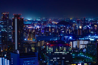 Illuminated cityscape against sky at night