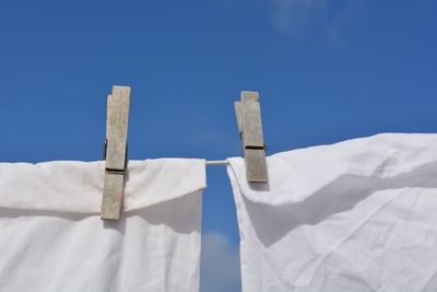 Low angle view of white hanging against blue sky