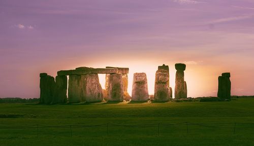 Built structure on field against sky at sunset