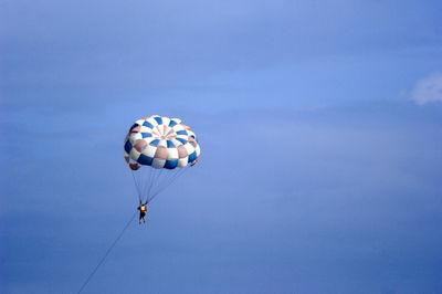 Low angle view of person paragliding against blue sky