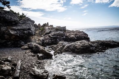 Rock formation on beach against sky