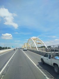 Vehicles on road against sky in city