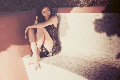 Young woman sitting on seat during sunny day