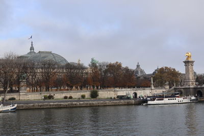 Buildings by river against sky