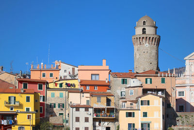 Low angle view of buildings in town against clear blue sky