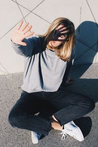 High angle view of young woman shielding while sitting on road