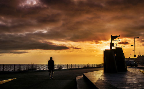 Silhouette man on bridge against sky during sunset