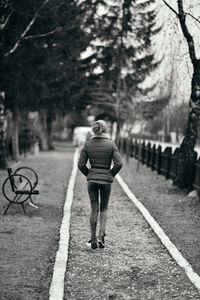 Rear view of man walking on footpath