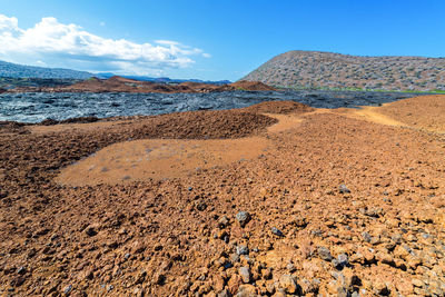 Barren landscape by dry lava against blue sky at galapagos islands