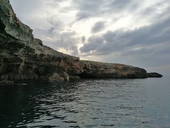 Rock formations by sea against sky