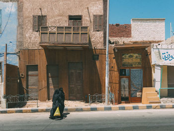 Rear view of woman walking against building in city