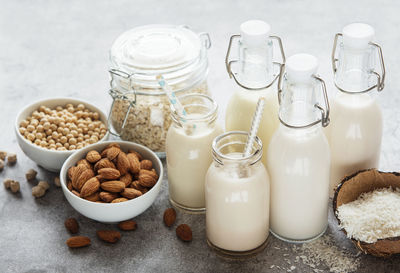 Alternative types of vegan milks in glass bottles on a concrete background. top view