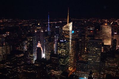 Illuminated bank of america tower amidst buildings at manhattan