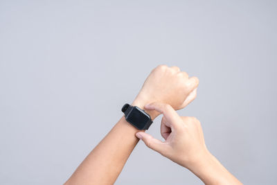 Close-up of hand holding clock over white background