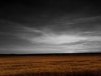 Scenic view of field against cloudy sky