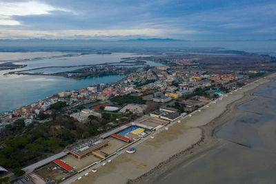 Aerial view of buildings by sea against sky