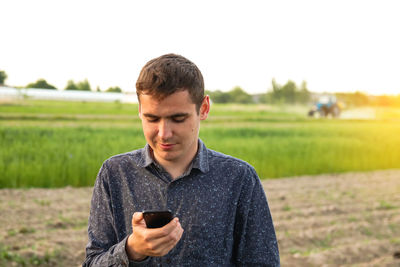 Young man using mobile phone while standing on field