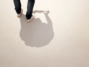 Low section of person standing on footpath during sunny day